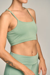 Person wearing a green sports bra and leggings against a neutral background