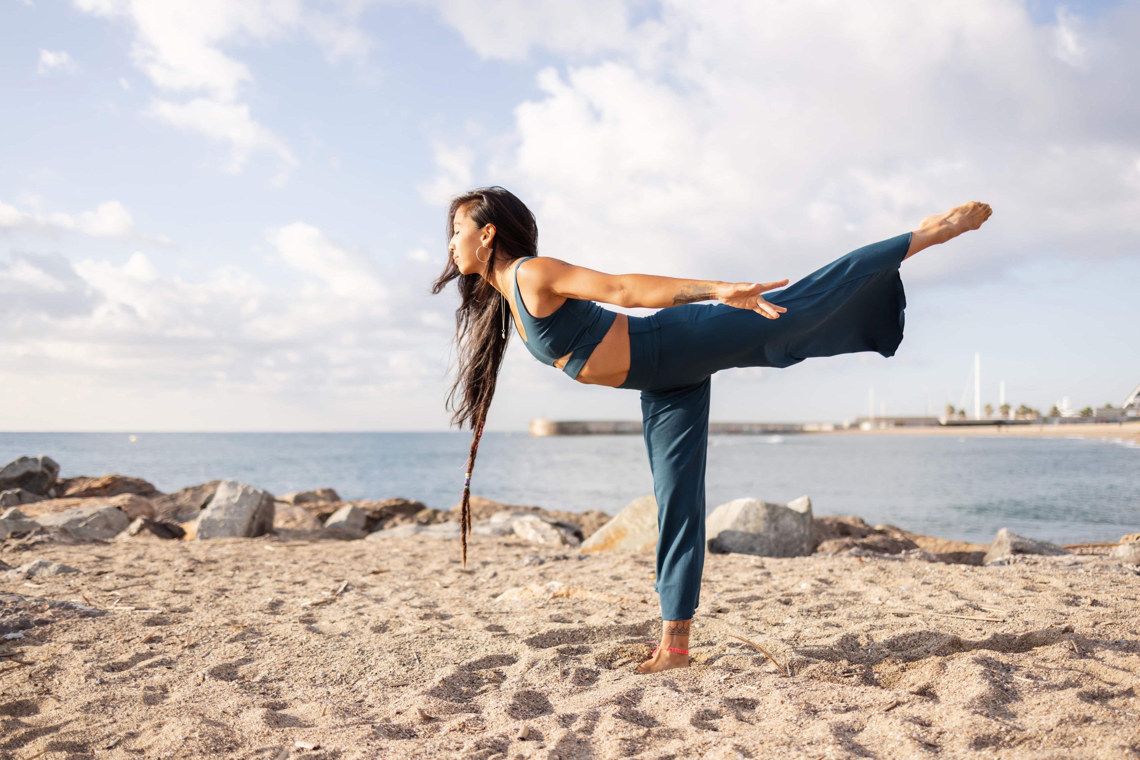 Sustainable yoga practice by the sea - woman in eco-friendly bamboo yoga wear from Shambhala, embodying harmony with nature